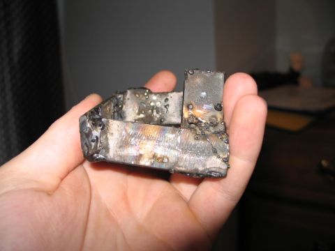 1995 Ford Bronco - A crudely welded metal part is held in a person's hand, with visible weld marks and discoloration.