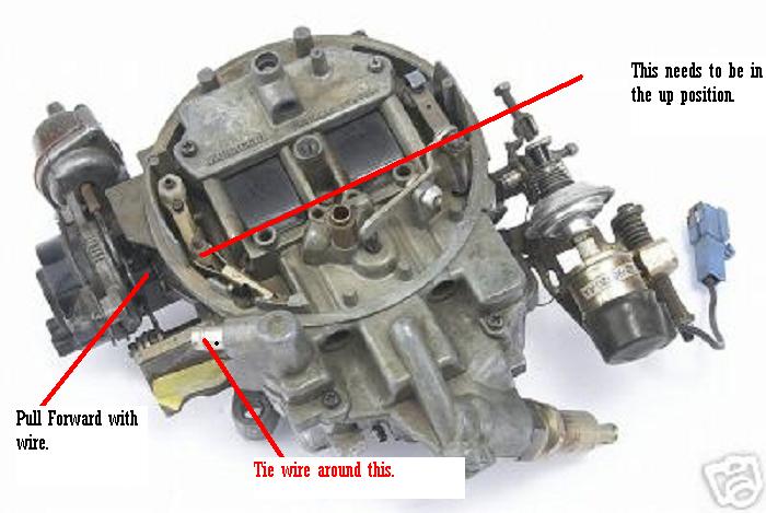 Close-up of a carburetor with red lines and text indicating adjustments