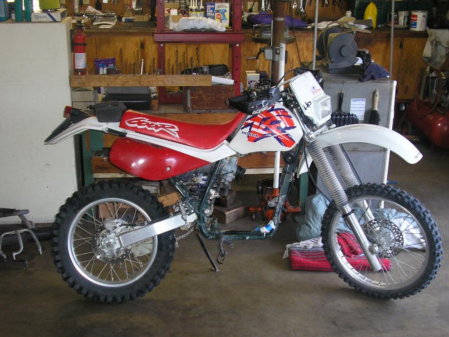 Side view of a white and red Honda dirt bike with 'CRF' on the seat