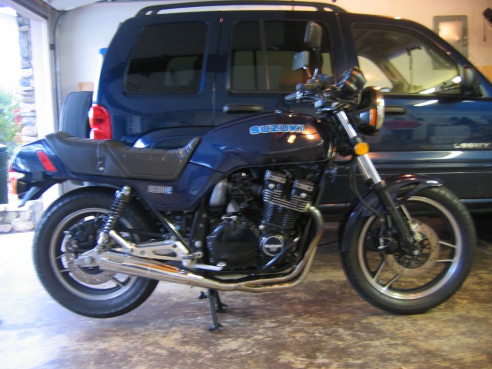 Blue Suzuki GS1100E motorcycle parked next to a dark blue SUV