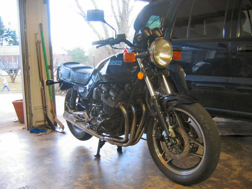 Front view of a black Suzuki motorcycle parked in a garage