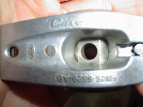 1984 Ford Bronco - A metal engine component is shown in detail, with visible stamping and a central opening.