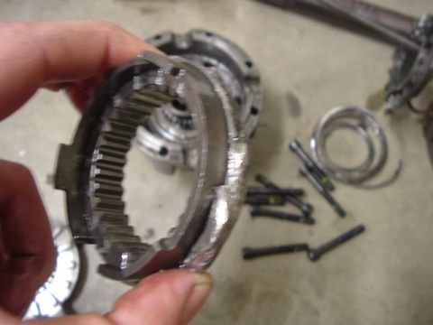 1999 Jeep Grand Cherokee - A close-up shows a damaged metal gear component, likely from a vehicle's transmission or drivetrain, with other related parts and fasteners…
