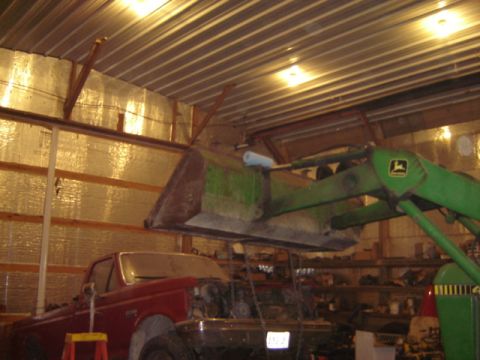 1992 Ford Bronco - A red pickup truck is partially disassembled inside a barn, with a front-end loader overhead.