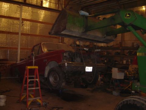1992 Ford Bronco - A red 1992 Ford Bronco is shown with its engine removed, suspended in a workshop.