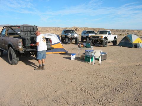 1997 Ford Ranger - Multiple off-road vehicles and camping equipment are set up in a desert environment under a clear blue sky.