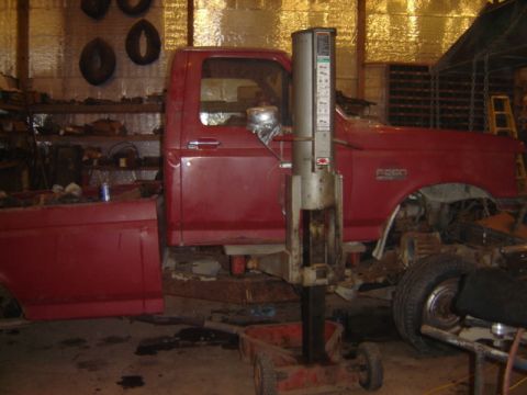 1992 Ford Bronco - A red 1992 Ford F-250 pickup truck is shown from the side, positioned on a lift inside a workshop.