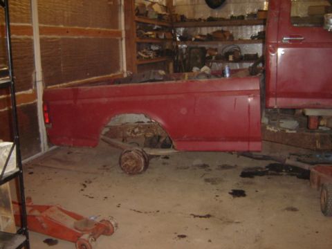 1992 Ford Bronco - A red 1992 Ford Bronco is shown in a garage, missing its rear axle and wheels, with the cab and bed visible.