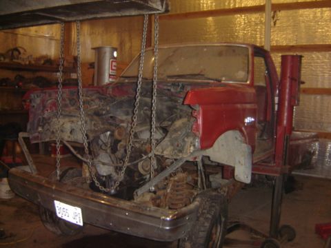 1992 Ford Bronco - 1992 Ford Bronco with engine removed, suspended by chains in a garage.