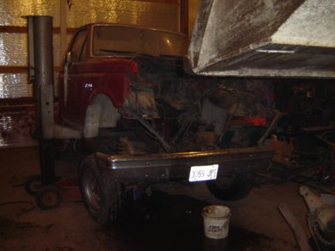 1992 Ford Bronco - A red truck, possibly a Ford F-series, is shown with its front end disassembled and lifted by a shop crane.