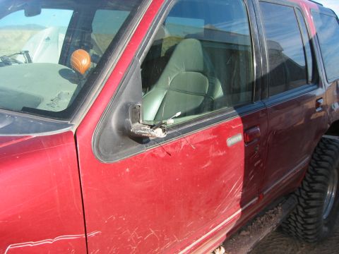 1997 Ford Ranger - The side mirror on this red SUV is broken and hanging loose.