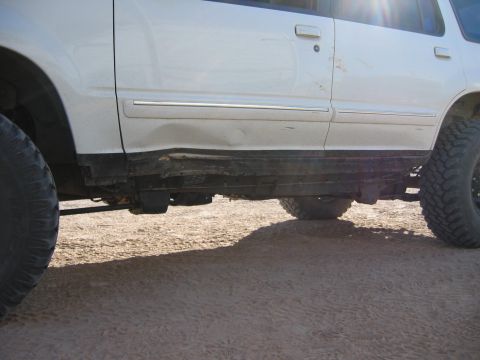 1997 Ford Ranger - This white SUV shows significant damage to its rocker panel and is equipped with large off-road tires.