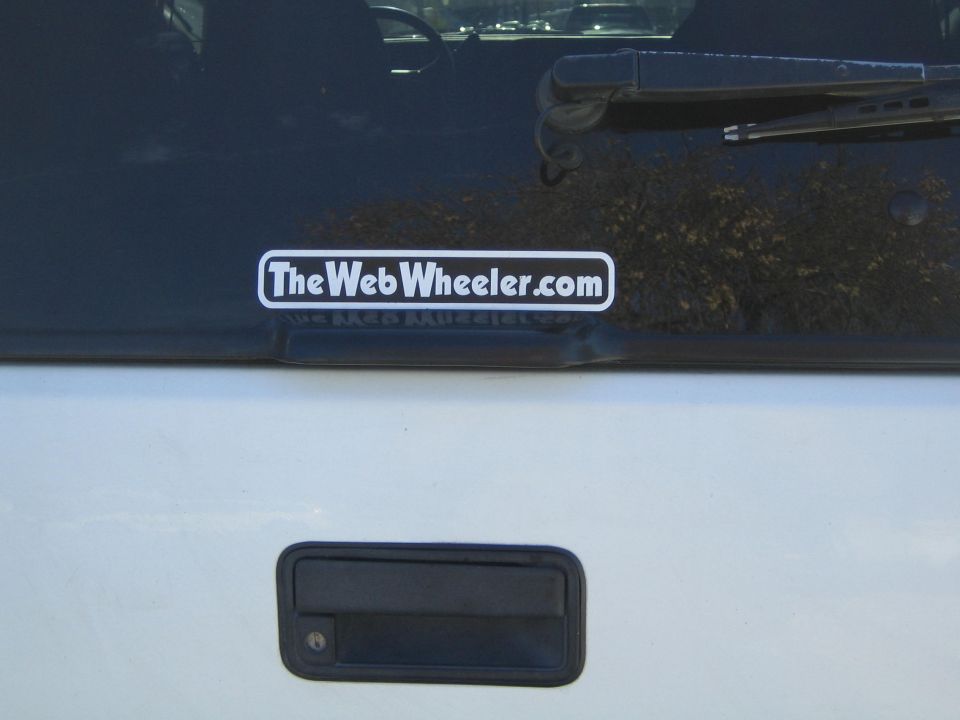 Rear window with TheWebWheeler.com sticker and black door handle