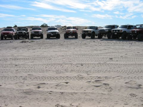 1997 Ford Ranger - Several trucks are parked in a row on a sandy surface with tire tracks visible.