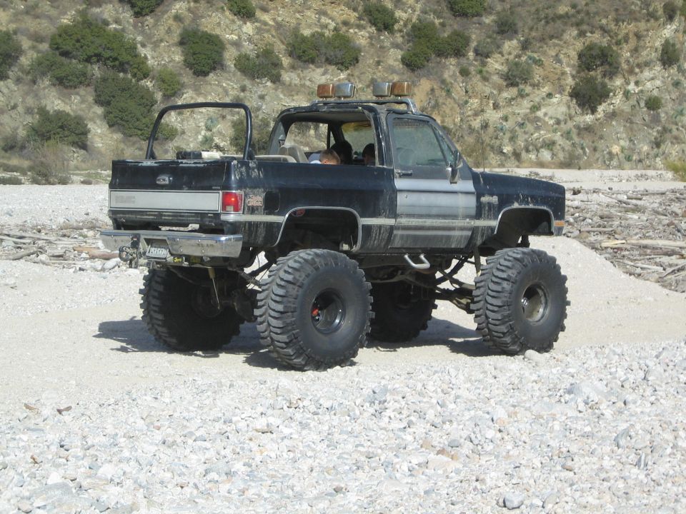 Black lifted pickup truck with large tires and off-road lights