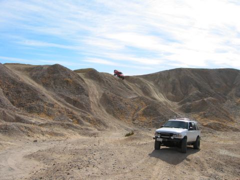 1997 Ford Ranger - Two off-road vehicles navigate a dusty, hilly landscape under a partly cloudy sky.