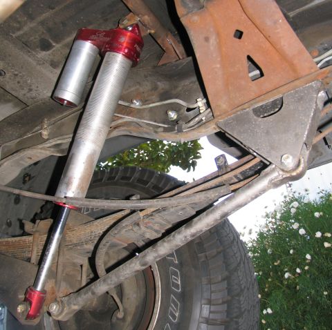 1984 Ford Bronco - Close-up view of the rear suspension system, highlighting an aftermarket shock absorber and leaf springs.