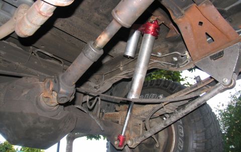 1984 Ford Bronco - Undercarriage detail of a vehicle's rear suspension system, including leaf springs and shock absorber.