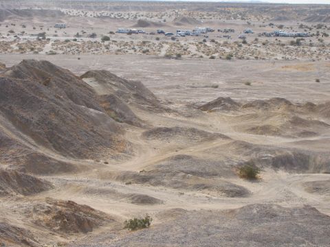 1997 Ford Ranger - A wide shot of a desert landscape with rolling hills and a distant gathering of vehicles.