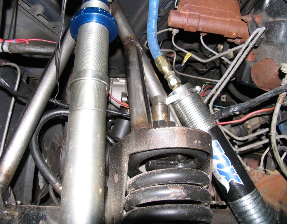 Engine bay with silver coilover shock, blue adjustable collar, and black Fox shock absorber