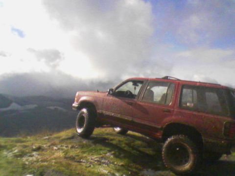 1991 Ford Explorer - A red 1991 Ford Explorer is parked on a grassy incline under a cloudy sky.
