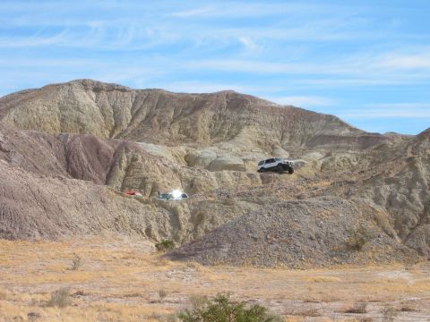 1997 Ford Ranger - SUVs navigate a desert landscape with layered rock formations and dry vegetation.