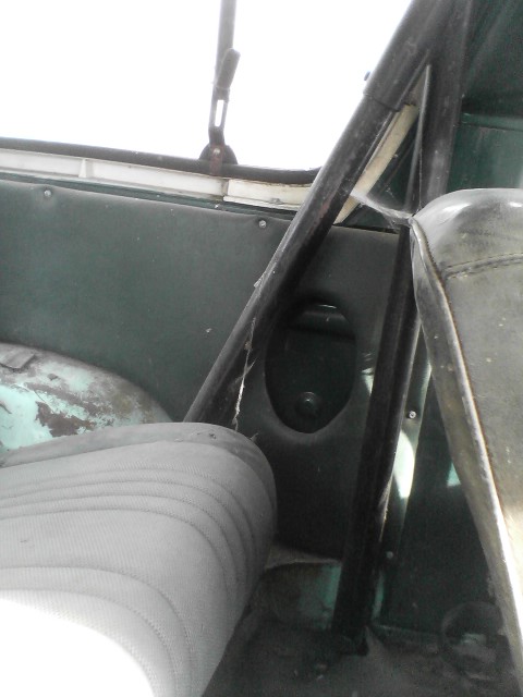 1978 Ford Bronco - The interior of an older vehicle shows wear and tear, with a roll cage and a partial view of the seat.