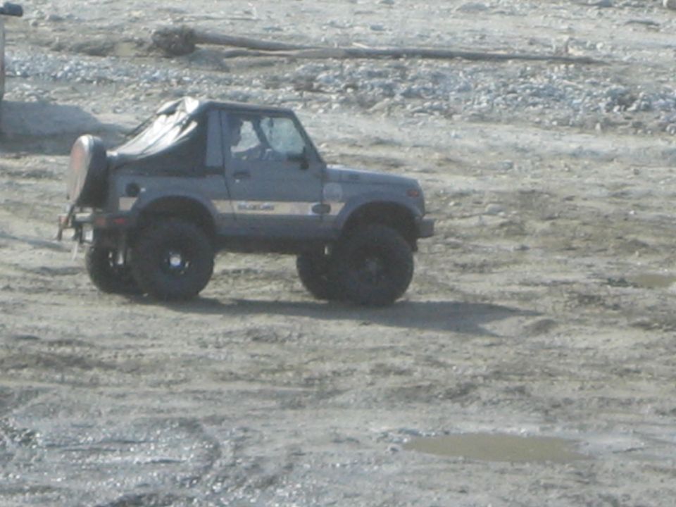 1987 Suzuki Samurai with soft top and spare tire on rear, parked on dirt