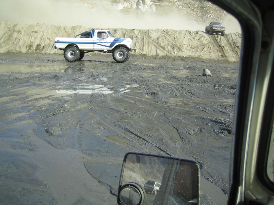 Lifted pickup truck with blue stripes driving through mud