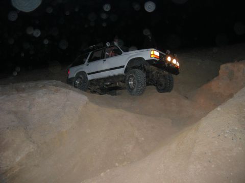 1997 Ford Ranger - A white 1997 Ford Ranger navigates a steep dirt incline in the dark, illuminated by its headlights.