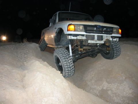 1997 Ford Ranger - This lifted pickup truck navigates a sandy incline in the dark, with one headlight visible in the distance.