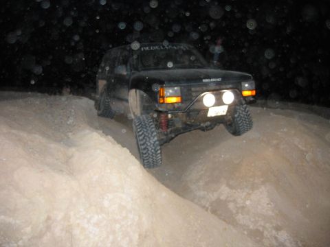 1997 Ford Ranger - This modified SUV navigates a sandy terrain under the cover of darkness, its headlights cutting through the night.