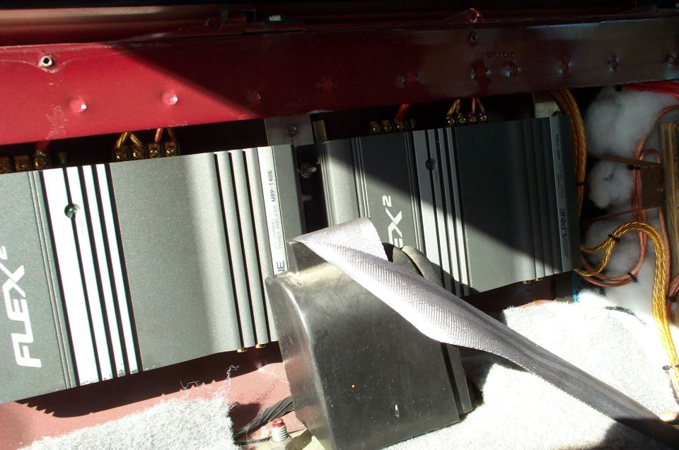 Two car audio amplifiers labeled FLEX 2 and ALPINE, with wiring and a seatbelt