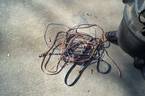 1996 Ford Bronco - A tangled mess of electrical wires lies on a concrete surface next to a vehicle's tire.
