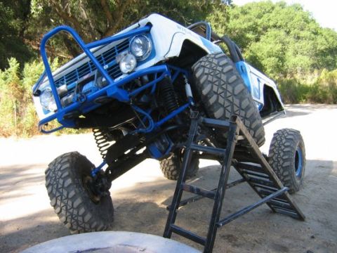 1971 Ford Bronco - This heavily modified vehicle is positioned on a ramp, its off-road capabilities and custom blue roll cage.