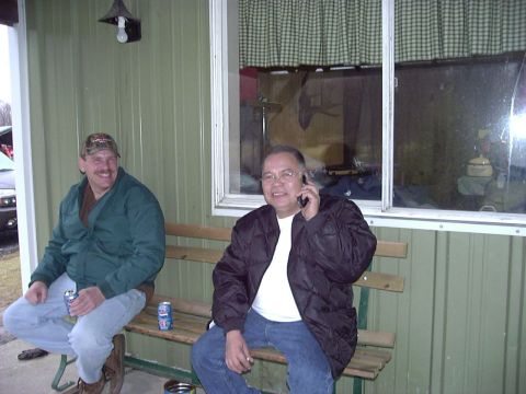 1992 Ford Bronco - Two men relax on a bench outside a building, one talking on a cell phone.