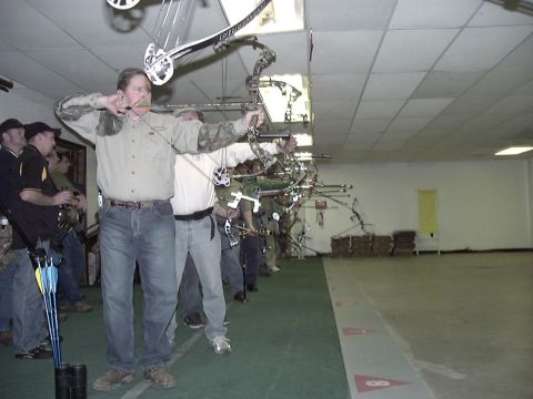 1992 Ford Bronco - Several individuals are lined up, drawing their bows in an indoor archery range.