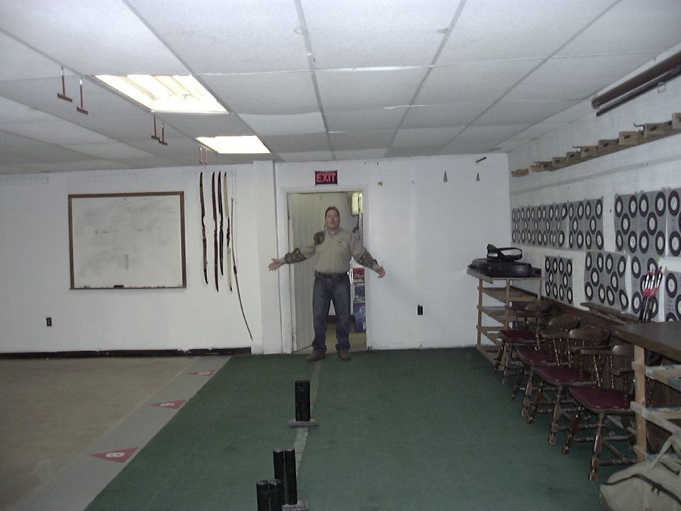 Interior scene with archery targets on the wall and a man standing in a doorway