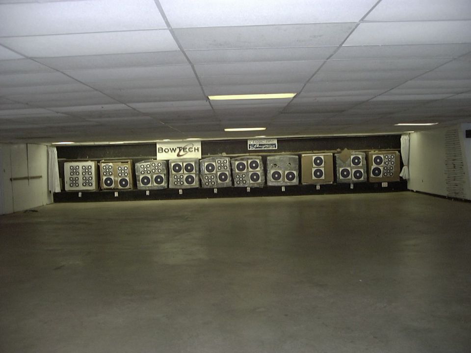 Indoor archery range with multiple targets lined up on a wall