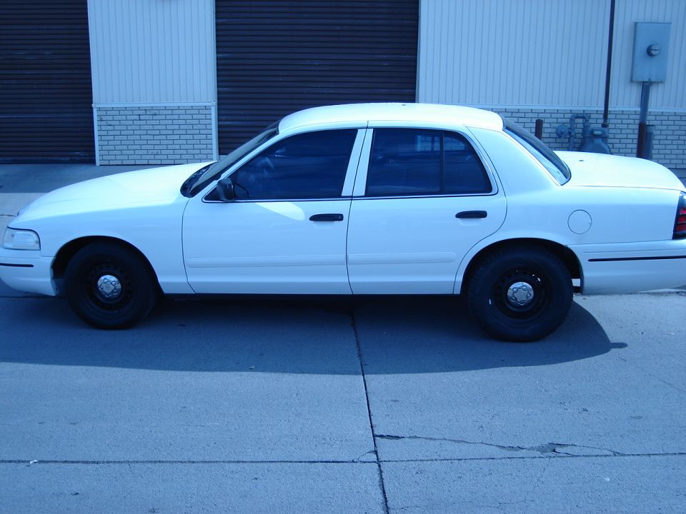 White 2000 Ford Crown Victoria sedan, side view, black steel wheels, tinted windows, parked on asphalt