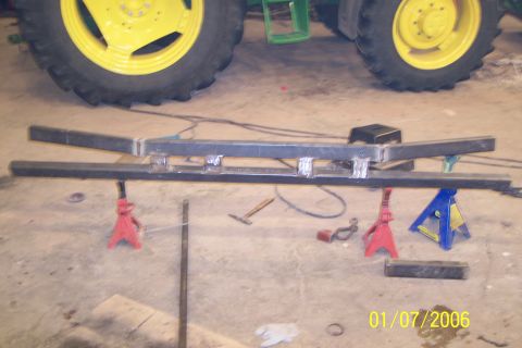 1986 Ford F-250 - A custom-fabricated bumper is supported by jack stands, with large tractor tires in the background.