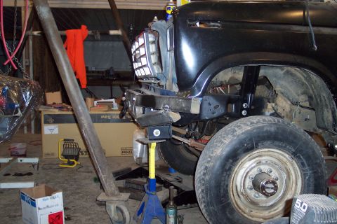 1986 Ford F-250 - Front end of a black truck, possibly from the 1980s, is raised on jacks with the grille removed for maintenance.