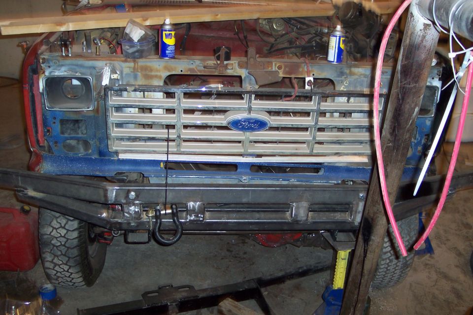 Ford truck front end with chrome grille and blue bumper, undergoing repairs