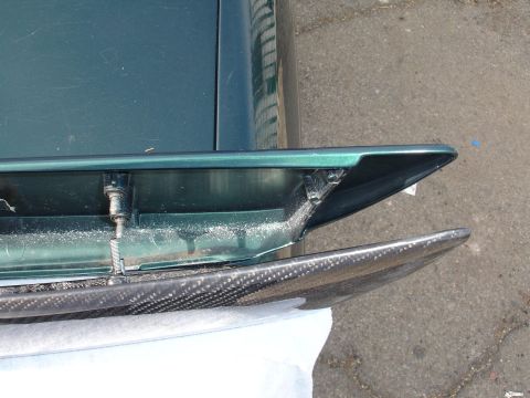 1995 Ford Taurus - A carbon fiber spoiler is attached to the green body of a car.