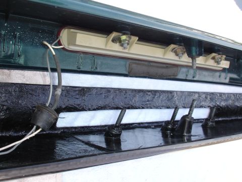 1995 Ford Taurus - The underside of a car's trunk lid reveals wiring and mounting bolts for a light fixture.