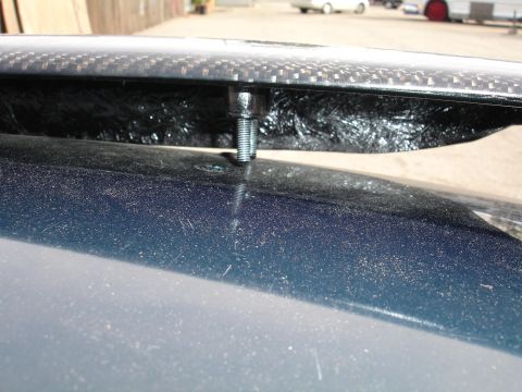 1995 Ford Taurus - Bolt securing a carbon fiber spoiler to a car's body, showing the mounting hardware.