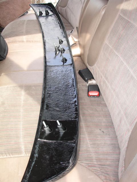1995 Ford Taurus - A black car spoiler is placed on the back seat of a car, with seat belts visible.