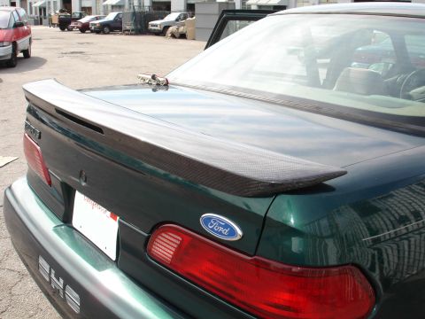 1995 Ford Taurus - Rear view of a green 1995 Ford Taurus sedan equipped with a carbon fiber spoiler and a Ford emblem.