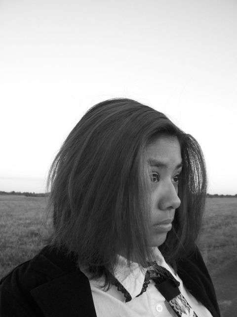1994 Ford Probe - A woman stands in a field, her profile visible against a pale sky, with her hair blowing in the wind.