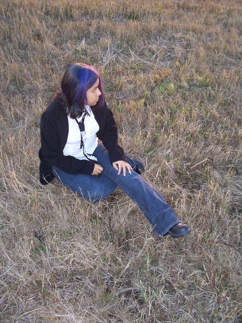 1994 Ford Probe - A person sits in a field of dry grass, looking off to the side.